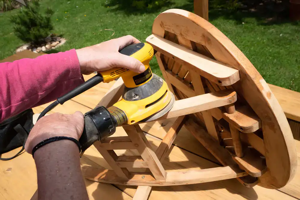 Restorer sanding and polishing a wooden chair arm